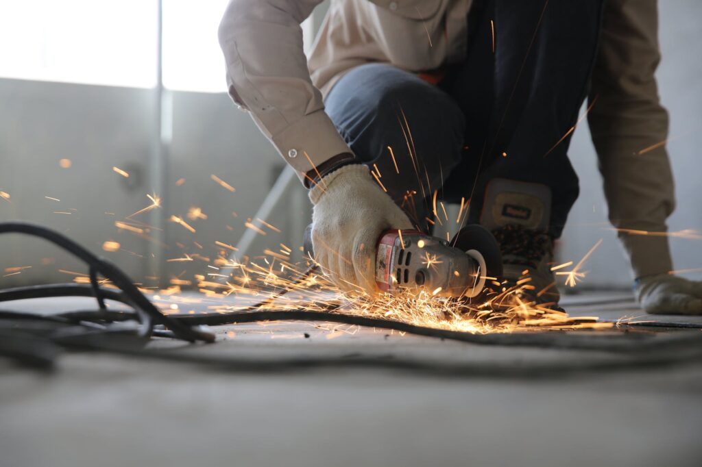 A skilled industrial worker uses a grinder creating a burst of sparks indoors.